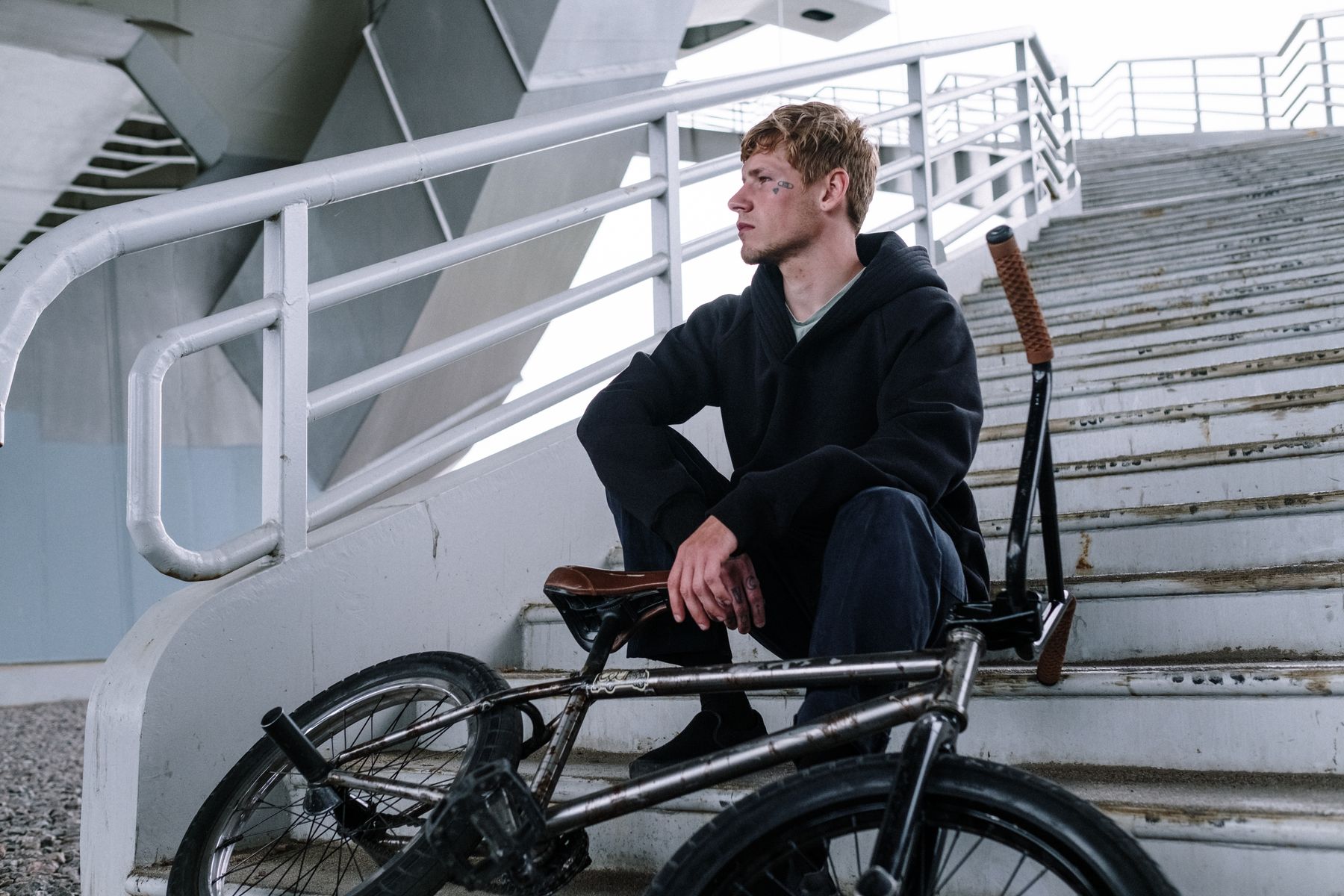 Rider resting with a bike on concrete city steps — photo by cottonbro studio on Pexels