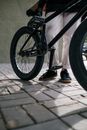 Person in Black Pants and Black Shoes Standing Beside Black Bicycle