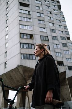 高加索女人与金发，站在自行车旁的现代建筑边