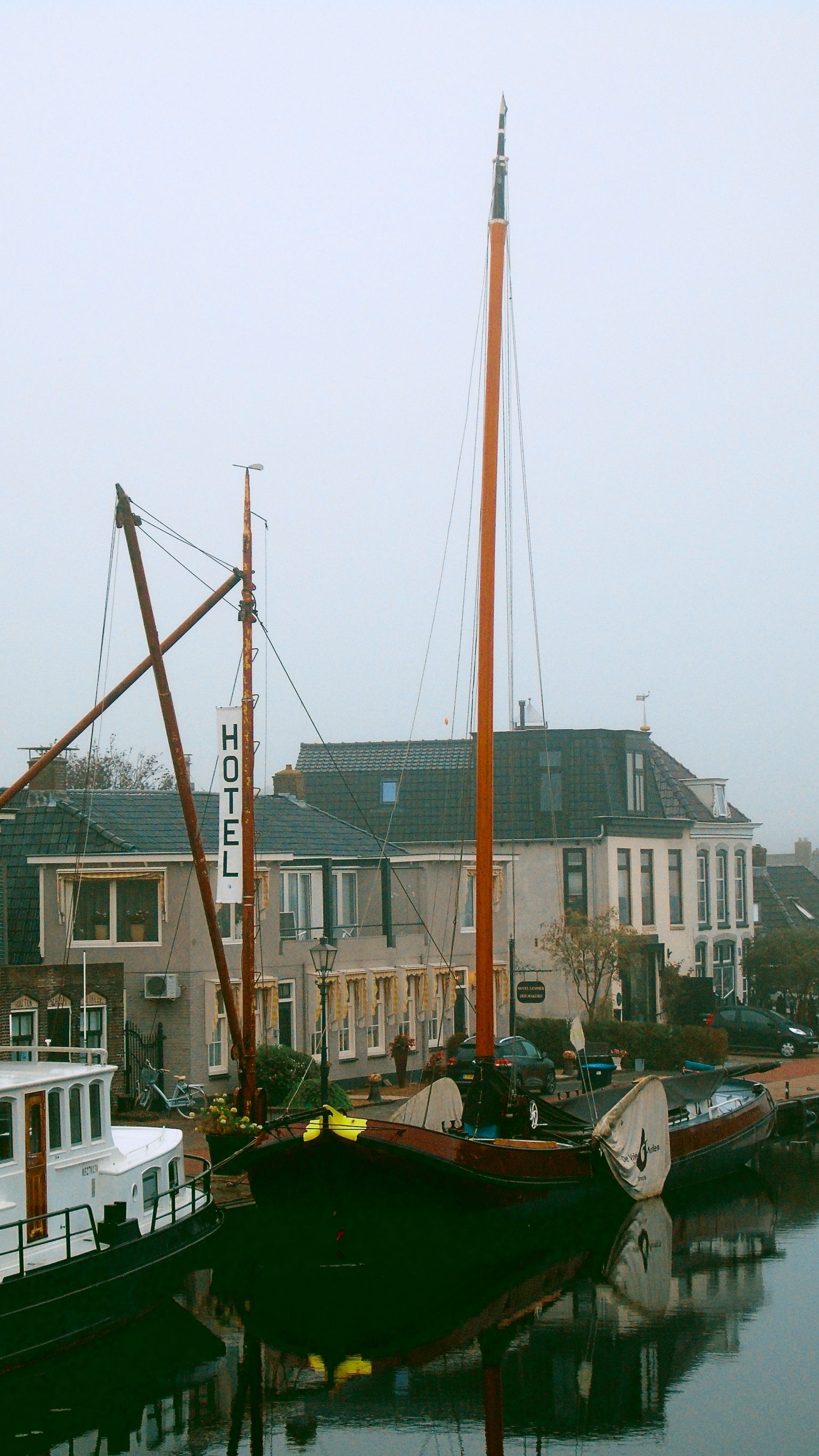 Serene canal scene featuring traditional boats moored beside a historic building on a foggy day.