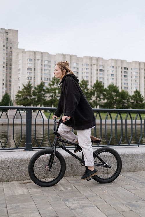 Woman Wearing a Black Hoodie Riding a Bicycle 