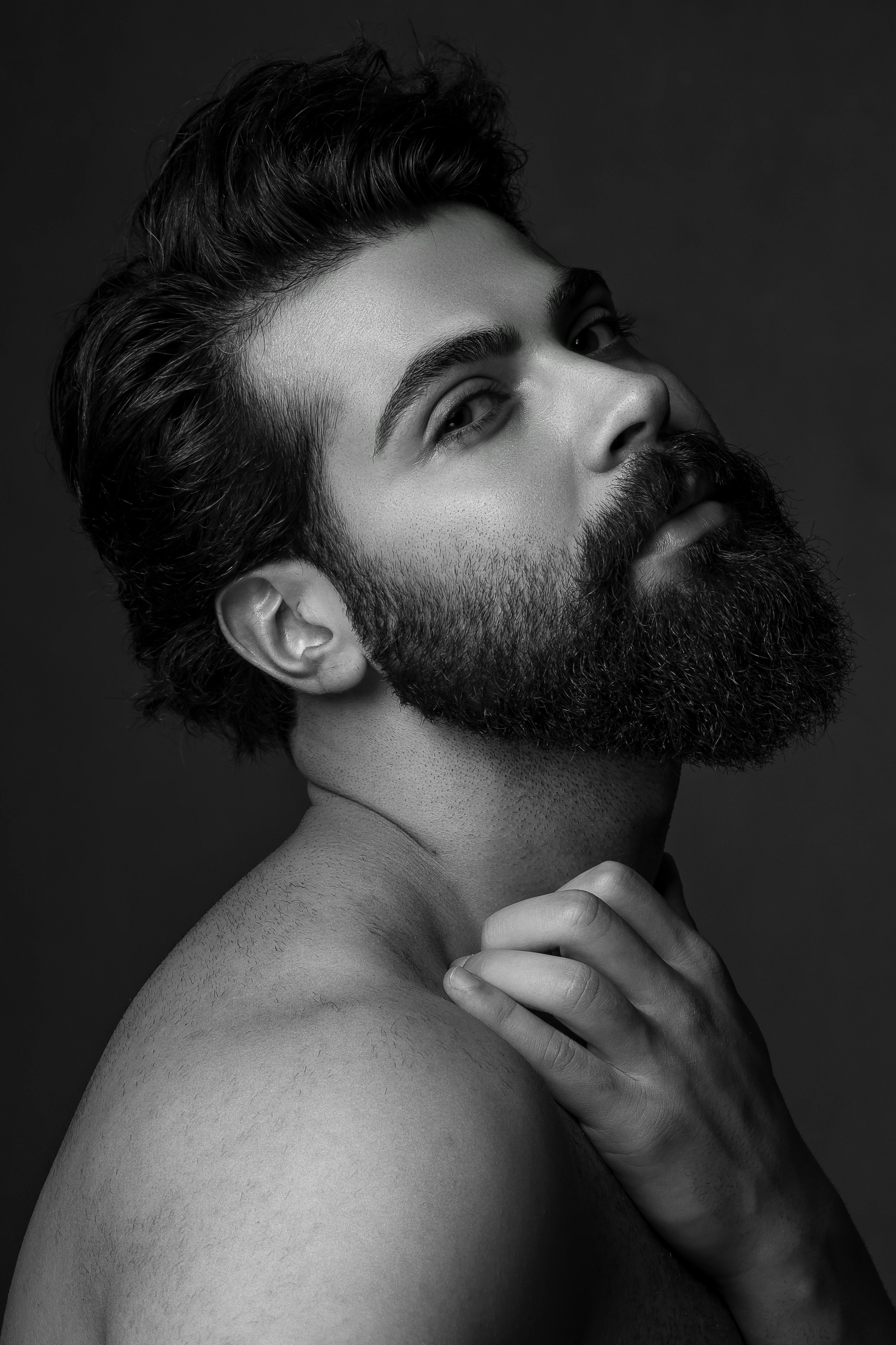 bearded man with trendy hairstyle touching neck