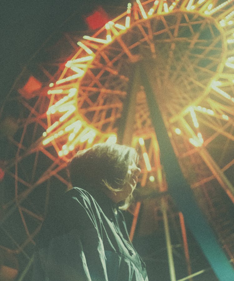 Calm Woman Against Bright Luminous Ferris Wheel At Night