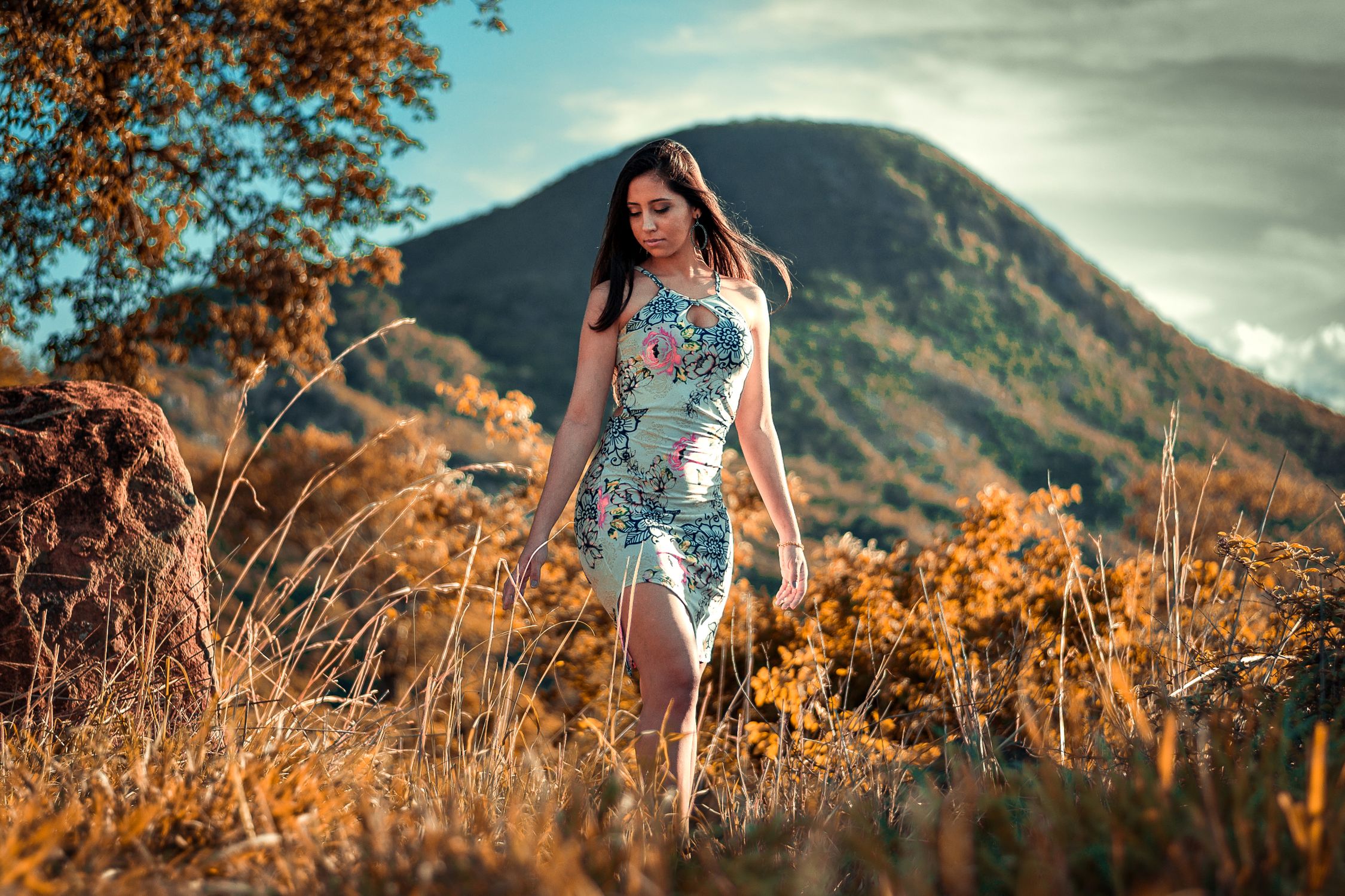 Mulher caminhando em trilha na natureza, expressão tranquila e presente, luz natural