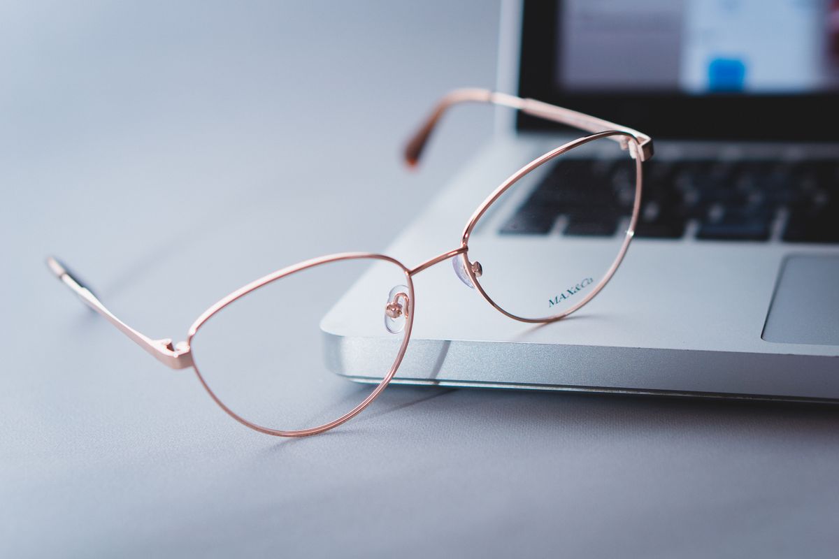 Unas gafas colocadas junto a un ordenador portátil sobre una mesa