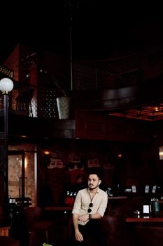 Elegant bar interior scene with man seated, featuring artistic mural and warm lighting.