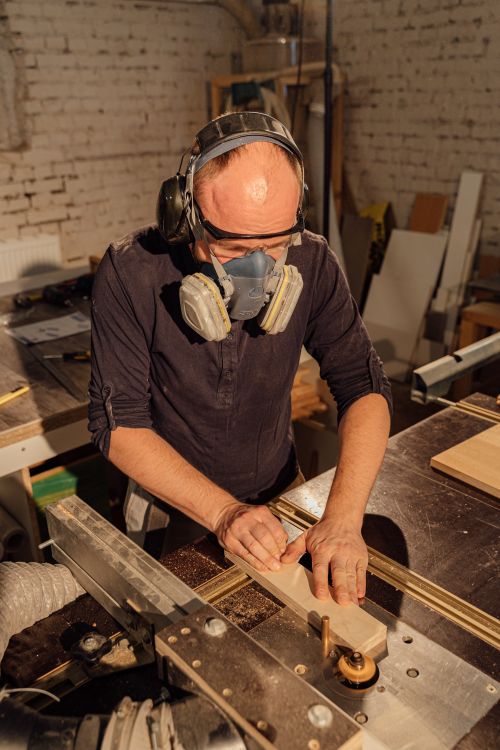 Free A skilled craftsman uses a table saw in a woodworking workshop, wearing safety gear. Stock Photo
