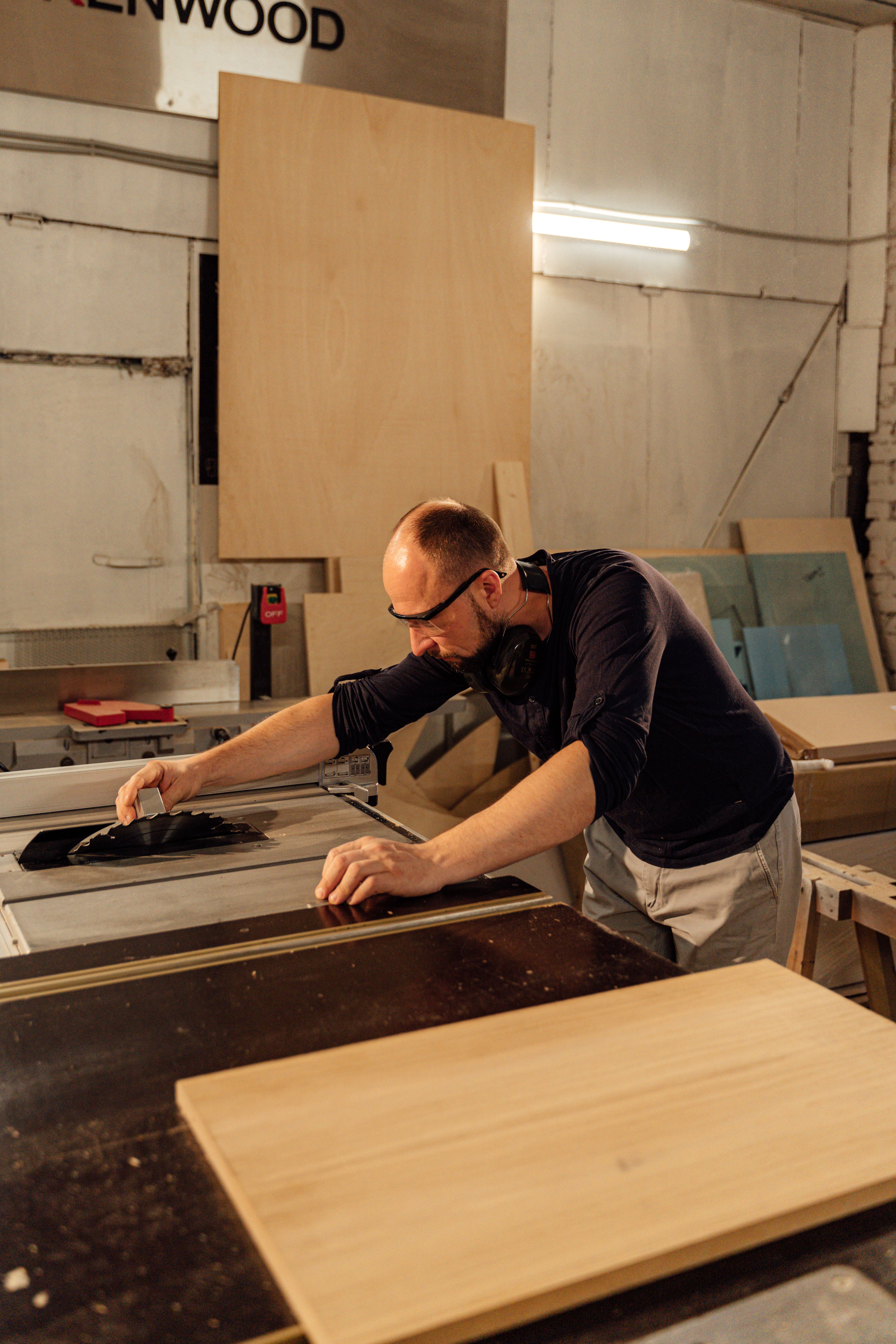 A craftsman operating machinery in a woodworking workshop.