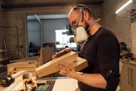 Man in Black T-shirt Wearing White Face Mask Holding Brown Wooden Board