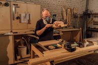 Man in Black Crew Neck T-shirt Holding Green and Black Power Tool