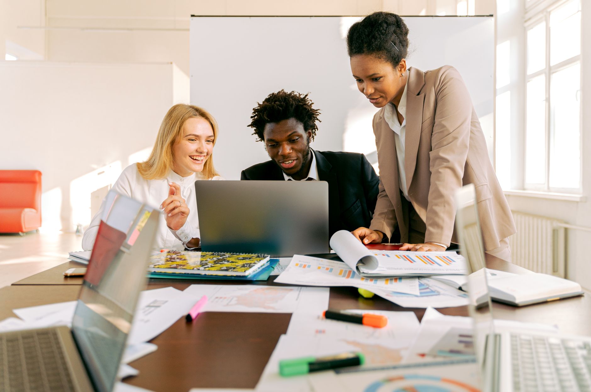 Diverse team collaborating on a project using laptops in a modern office setting