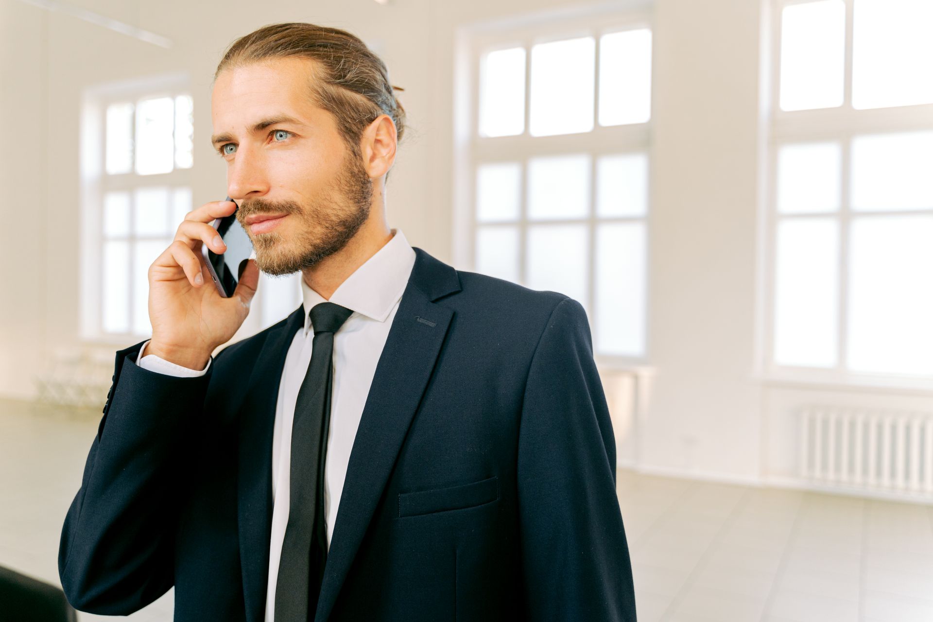 Confident businessman in a suit having a phone call in a bright office setting.
