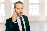 一位穿着正式西装的自信商人正在光线充足的现代办公室里打电话