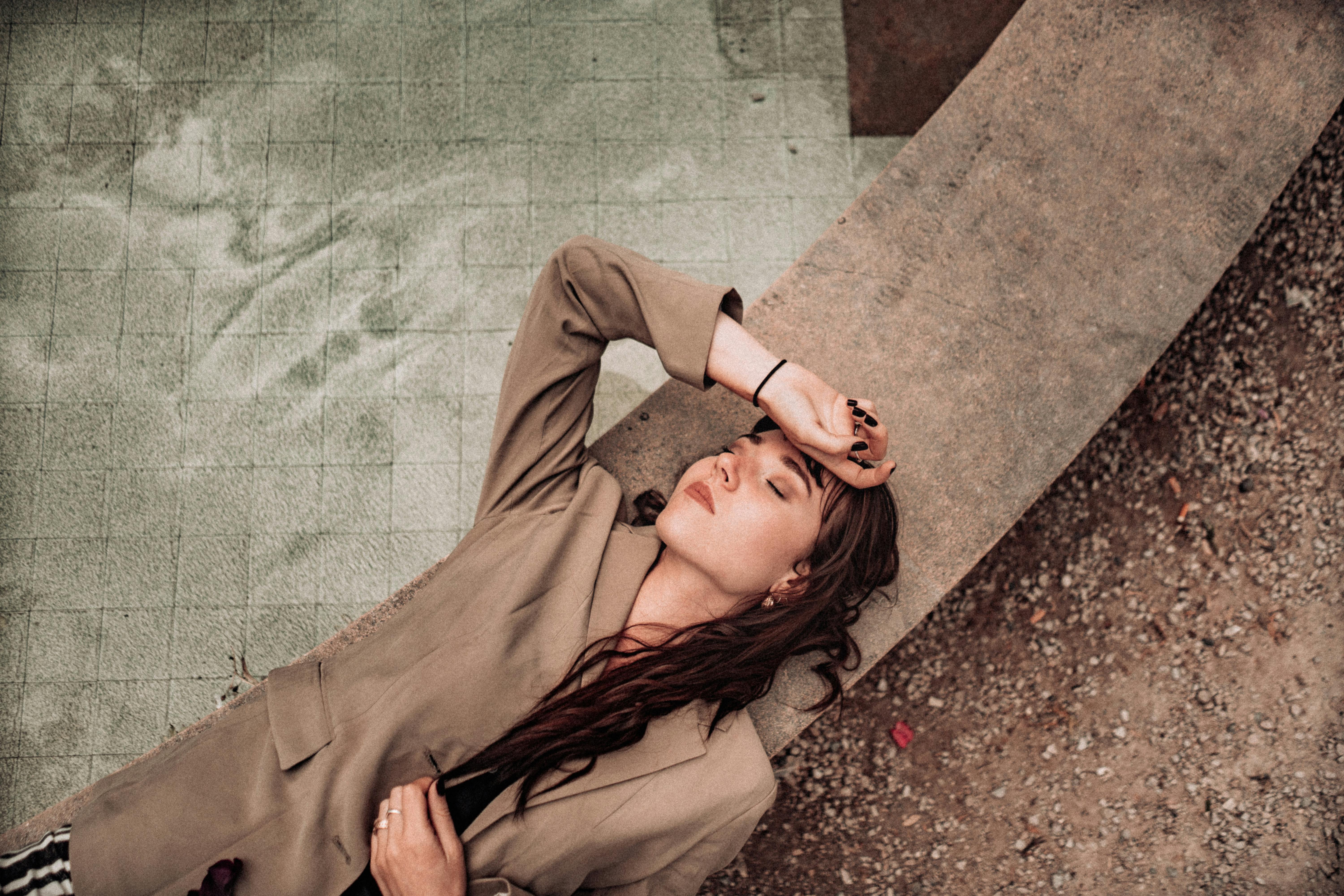 一位时髦的黑发女子闭着眼睛，在户外的长凳上休息