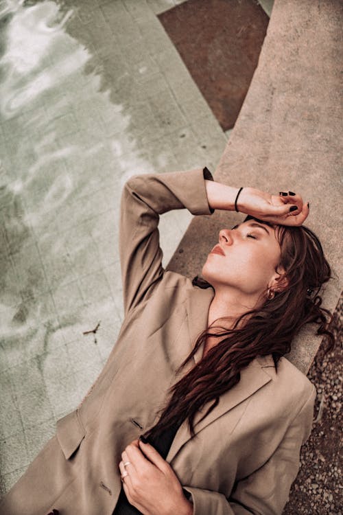 Woman Wearing Brown Blazer Lying on Poolside