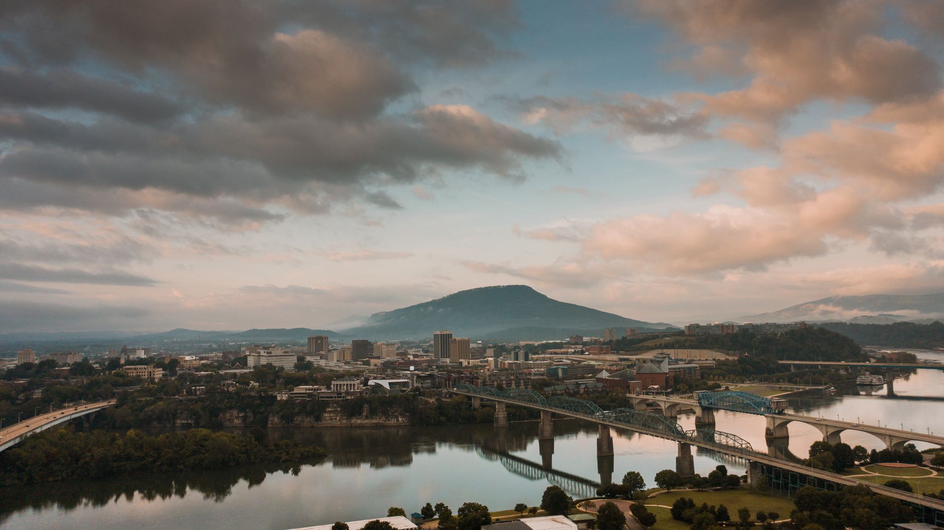 Picturesque scenery of modern bridges over Tennessee River flowing in Chattanooga city against cloudy sundown sky