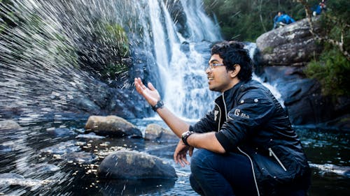 Free Man Sitting on Waterfalls Stock Photo