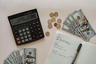 将计算器、现金、硬币和手写笔记平放，以便进行预算规划