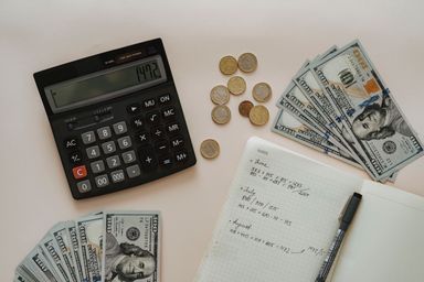 A calculator and pen resting on a printed ledger