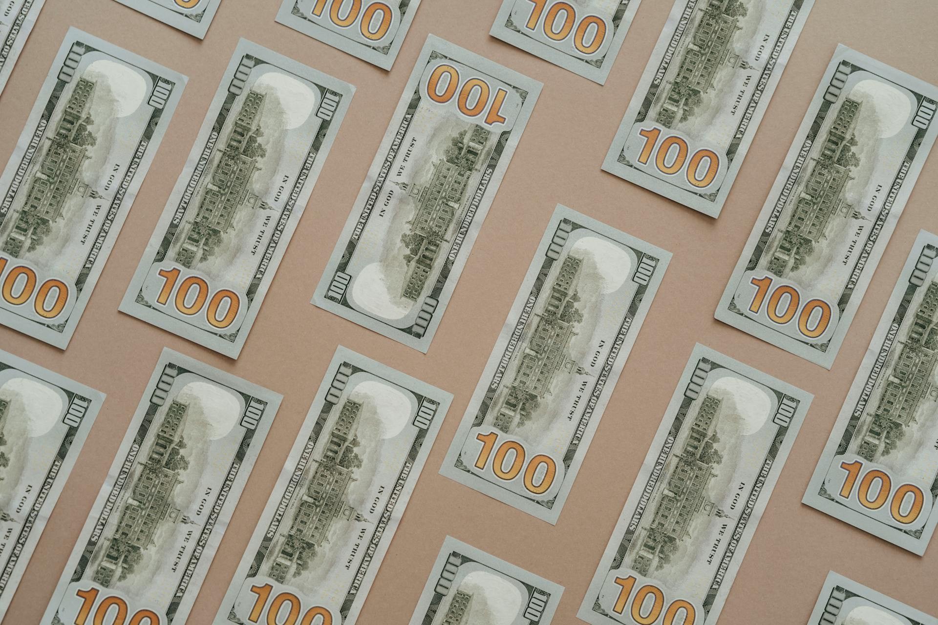 Patterned display of 100 US dollar bills, showcasing wealth and finance themes.