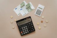 Black and Silver Calculator Beside Silver Coins