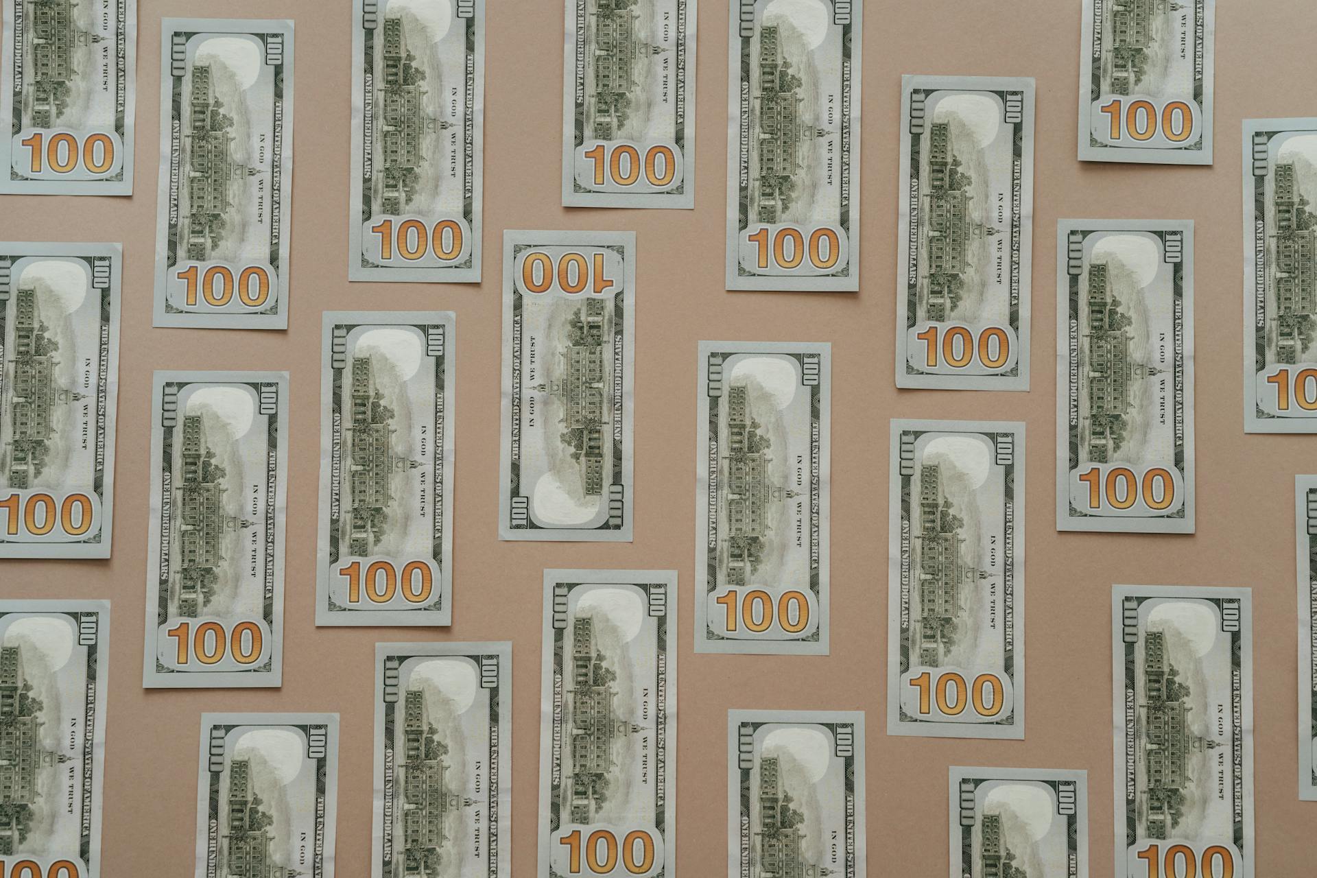 Flatlay of hundred dollar bills arranged on a surface representing wealth and finance.