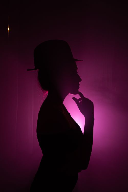 Free Artistic silhouette of a woman in a hat with a striking pink backlight, evoking mystery and elegance. Stock Photo