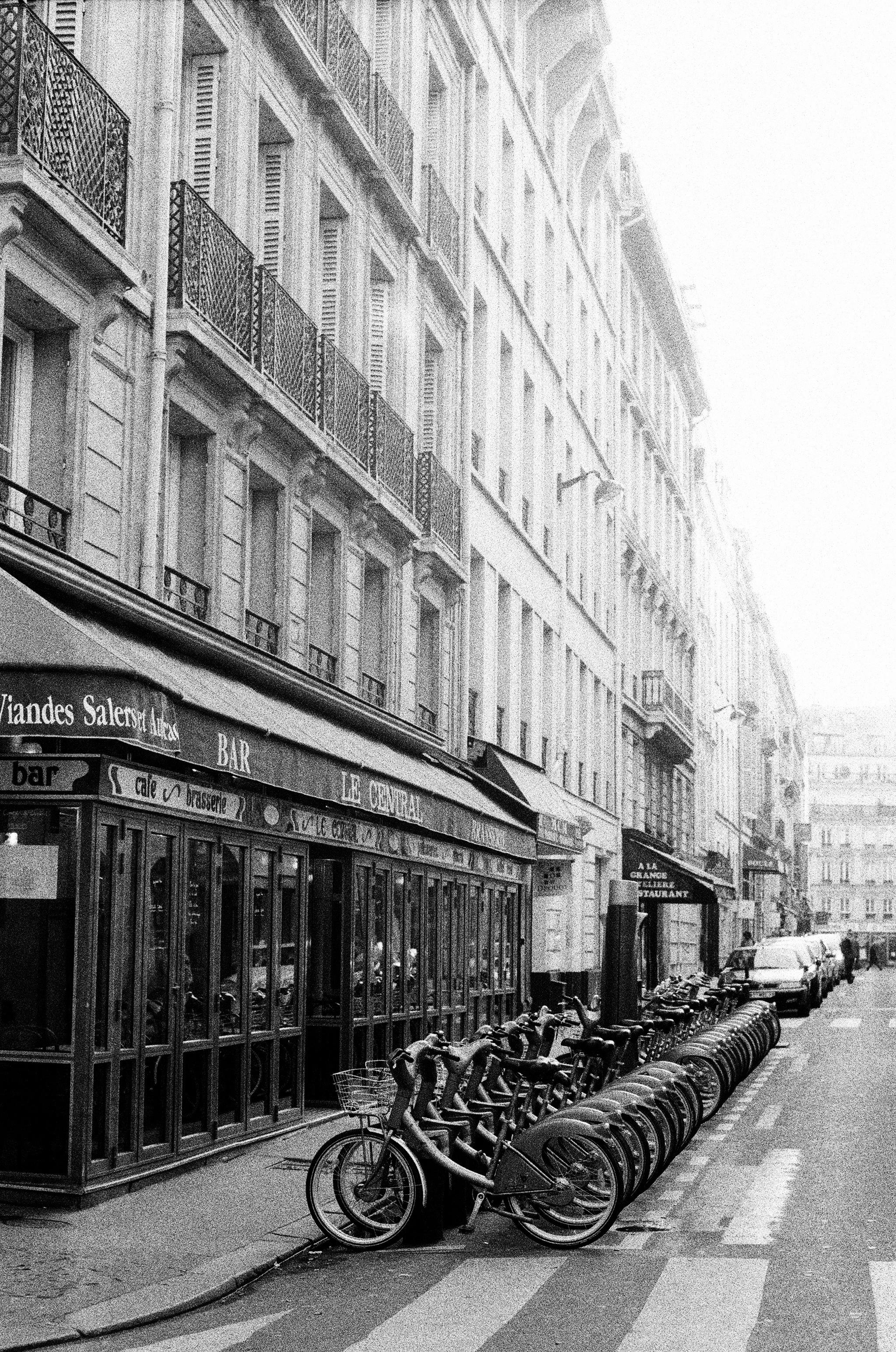 Black and white photo of a Paris street with bicycles and classic architecture.