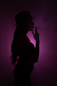 Artistic silhouette of a woman smoking with moody pink backlighting.