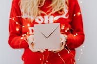 圣诞节的背景下，特写镜头里一个人手持一个被节日彩灯环绕的信封