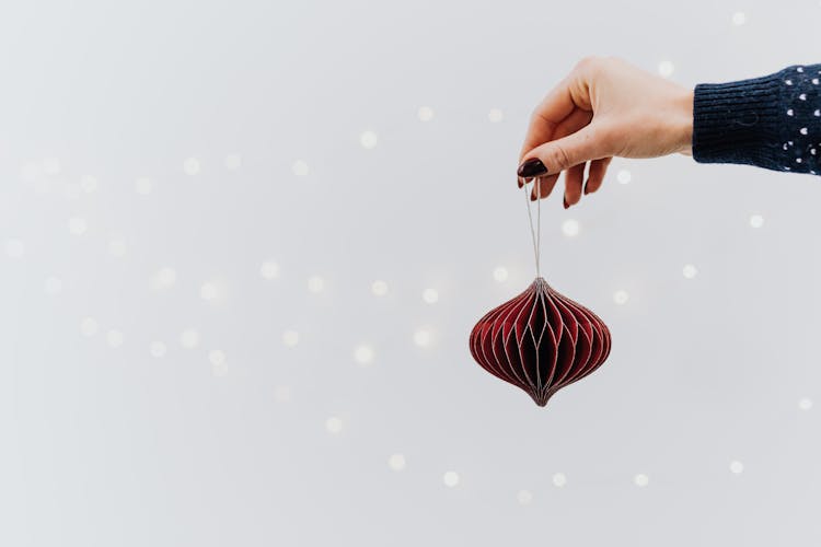 A Person Holding A Red Ball Shape Christmas Ornament