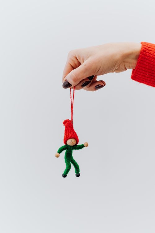 Free Close-up of a hand holding a cute Christmas ornament on a white background. Stock Photo