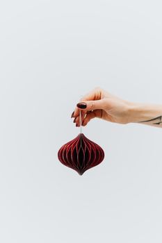 白色背景下，一只手特写拿着红色悬挂的圣诞装饰品