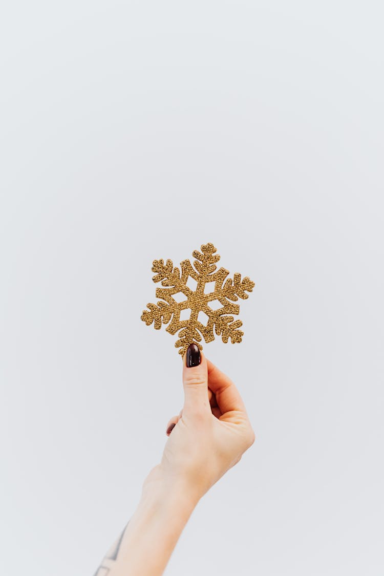 Person Holding Golden Snowflake