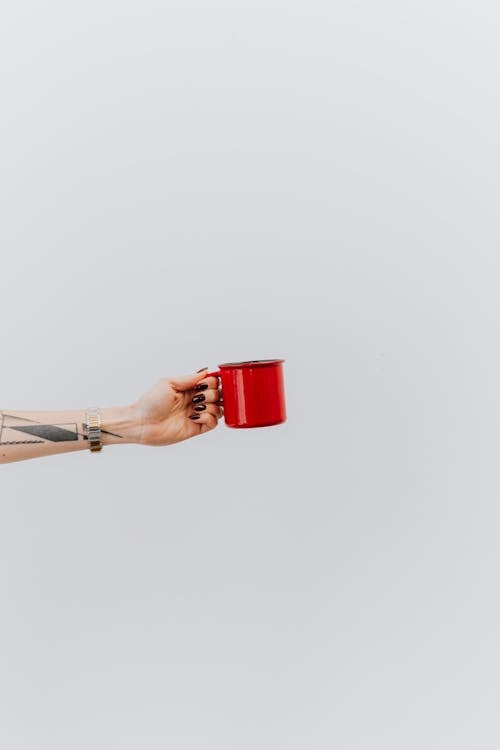 Person with Tattoo on Hand Holding Red Ceramic Mug