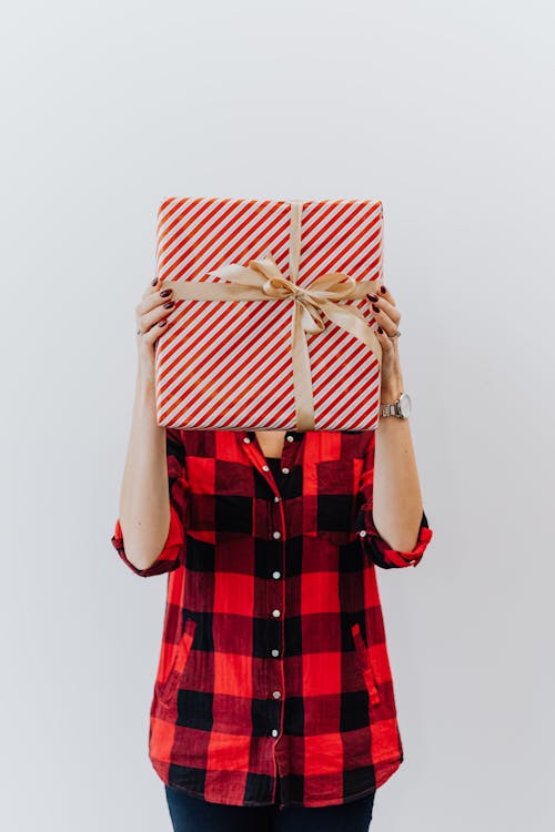 A Person in Checkered Long Sleeves Holding a Christmas Present