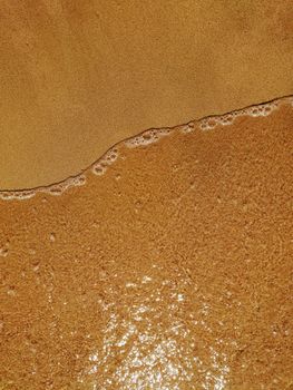 Top-down view of the tranquil sandy shoreline at Nha Trang, showcasing the gentle waves on a warm, sunny day.