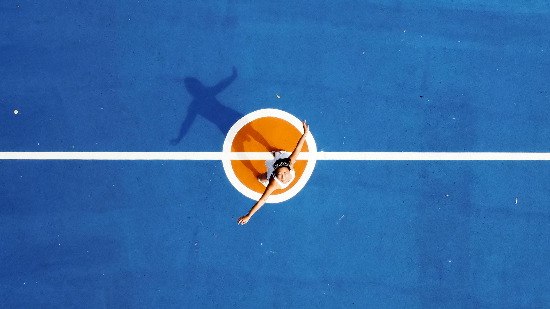 From above of young sportive female athlete in activewear on blue sports ground