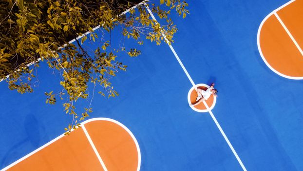 From above of female athlete in sportswear resting on sports ground in park