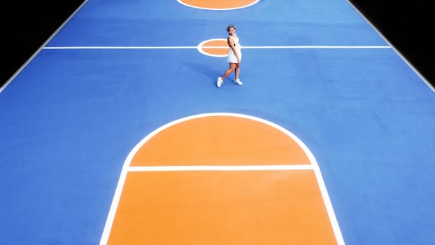 Woman standing on a colorful basketball court captured from above.