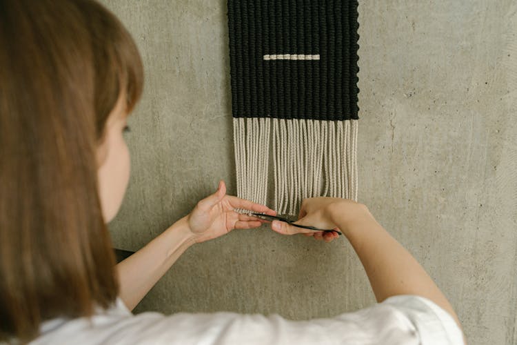 A Woman Cutting The Hanging Decoration On The Wall