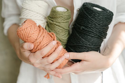 Close-up of hands holding colorful yarn spools, perfect for knitting enthusiasts.