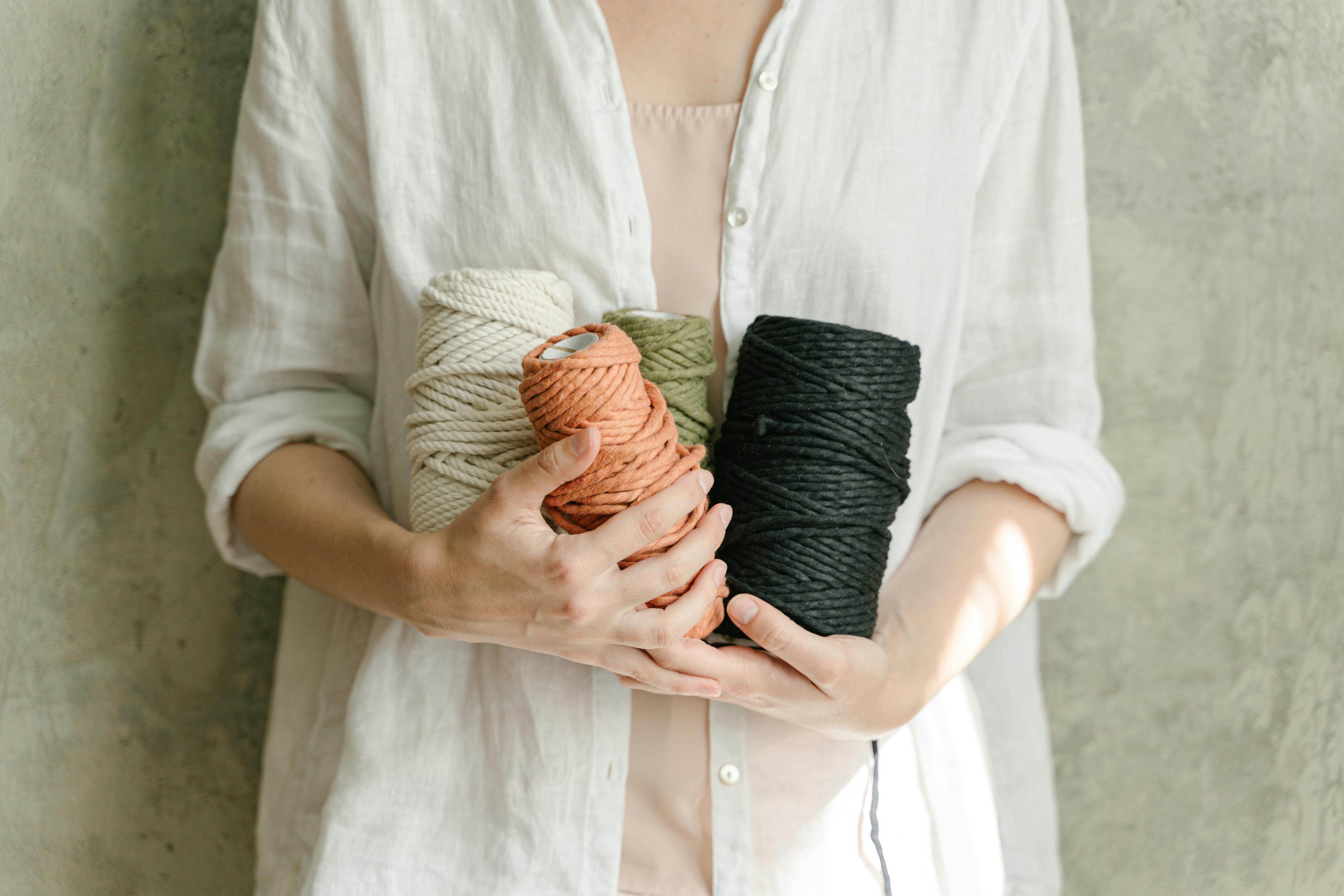 Person holding colorful yarns in a cozy indoor setting.