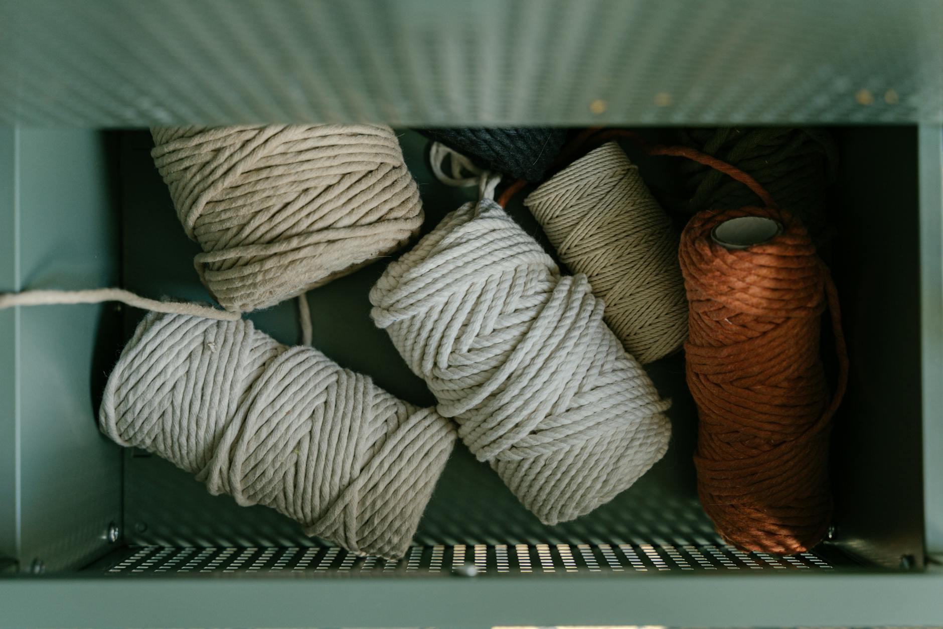 Various colored yarn balls neatly arranged in an open drawer viewed from above.