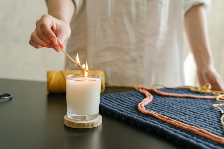  Hand Lighting A Candle On A Black Table Using A Matchstick