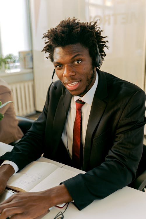 Free Man in Black Suit Sitting by the Table while Smiling at the Camera Stock Photo