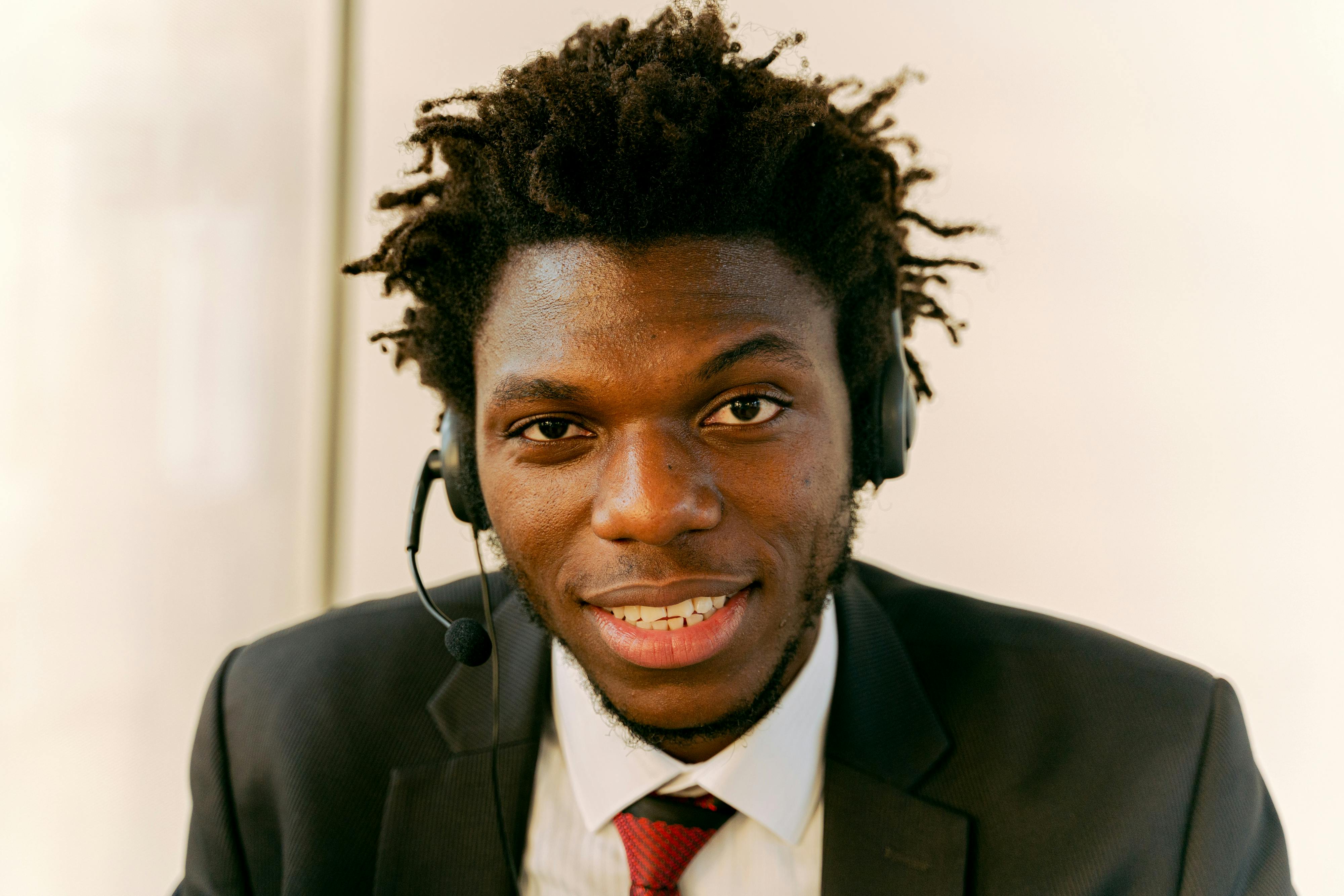 Professional call center agent wearing a suit and headset, smiling at the camera.