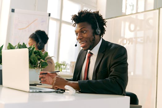Professional call center agent with headset working on a laptop in a modern office.