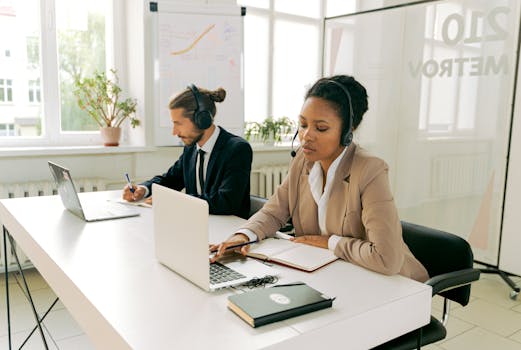 Office professionals wearing headsets, working on laptops, providing customer service.