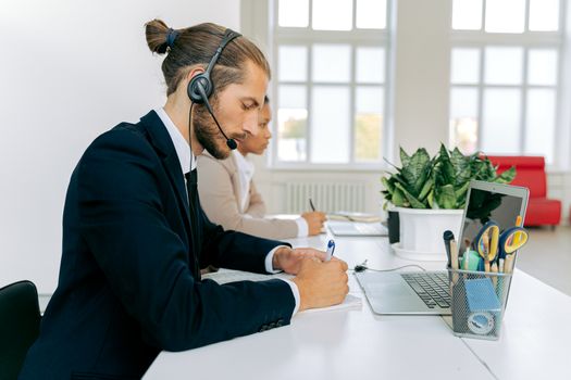 Customer service representative with headset working at office desk. Professional workspace environment.